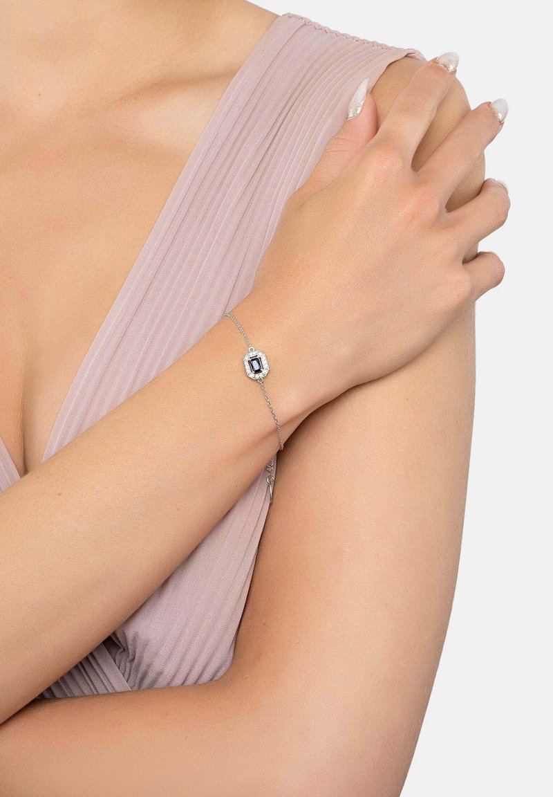 Hopeaketju hopeasta, jossa on suorakulmainen musta jalokivi, sekä huolellisesti valmistetut ketjureunat ja koristeelliset yksityiskohdat kiven ympärillä.