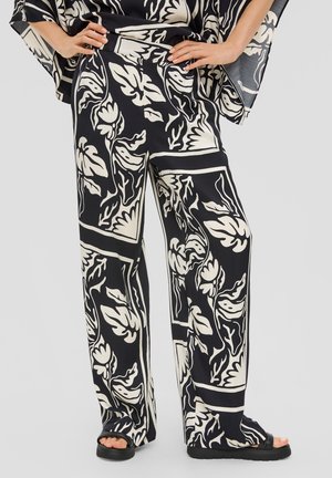 Pantalons larges noir et blanc avec un motif floral et des contours contrastés, fabriqués dans un tissu lisse avec une coupe décontractée.