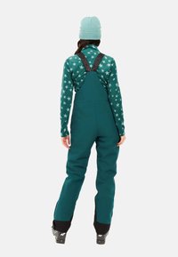 Teal skibroeken met verstelbare zwarte banden, met een waterdicht ontwerp en verstevigde zwarte manchetten. Draag je over een top met sterrenpatroon.