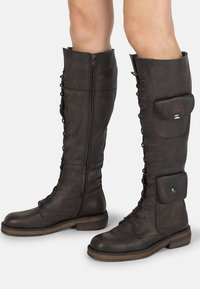 Botas de cuero marrón hasta la rodilla con cordones, cremallera lateral y un bolsillo lateral. Acabado texturizado y suela plana de madera.
