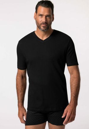 Camiseta de cuello en V negra de manga corta, hecha de tela de canalé, con un diseño texturizado y una silueta ajustada. Llevada con pantalones cortos negros con estampado.