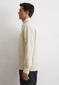 Lichtbeige langwerpige overhemd met een button-down kraag, enkele borstzak en afgeronde zoom. Gemaakt van een gestructureerde, ademende stof.