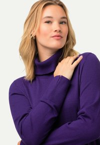 Maglione a collo alto viola realizzato in morbido tessuto a maglia, con maniche lunghe e sottili dettagli a coste vicino ai polsini.