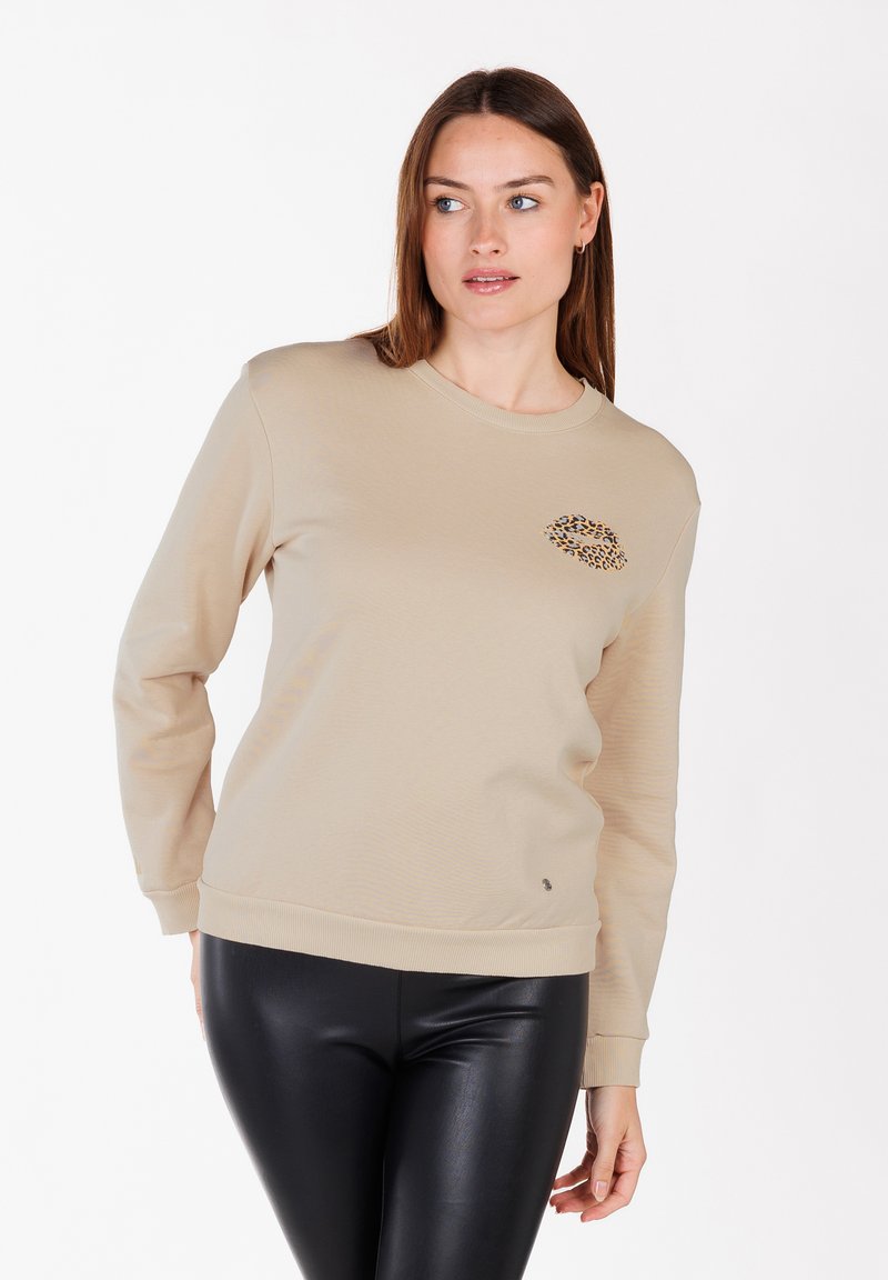 Felpa in cotone beige con scollatura rotonda, maniche lunghe, polsini a coste e dettaglio a stampa leopardata sul lato sinistro del petto.