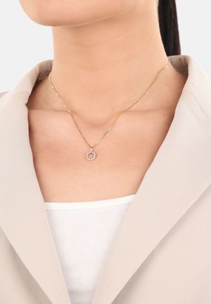Collar de cadena de oro con un colgante circular adornado con piedras transparentes. El colgante presenta una textura suave; la cadena tiene un diseño retorcido.