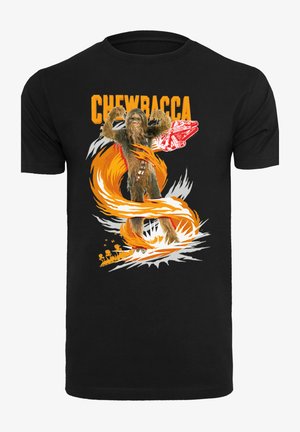 Sort bomuld T-shirt med et grafisk print af Chewbacca i orange og hvid, med en stiliseret eksplosion og et detaljeret rumskib i baggrunden.