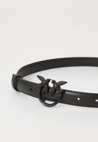Zwarte leren riem met een ronde gesp waarop twee gestileerde vogels zijn afgebeeld. De riem is glad en heeft meerdere verstelgaten.