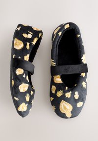 Pantofole nere con motivi grafici dorati di occhi, mani e altre forme. Il materiale è morbido peluche con suola strutturata e cinturino alla caviglia.