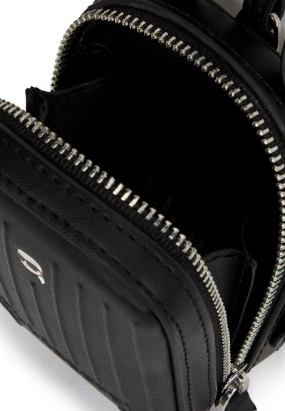 Sac en cuir noir avec un design texturé, zips en métal argenté et un compartiment principal zippé. Compact et élégant avec des détails de couture visibles.