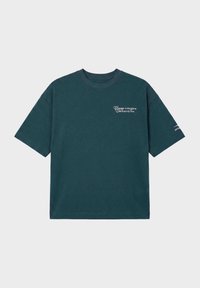 T-shirt vert foncé à manches courtes avec texte blanc "Change the game Cash Rules My Time" sur la partie supérieure gauche de la poitrine et petit motif sur la manche droite.