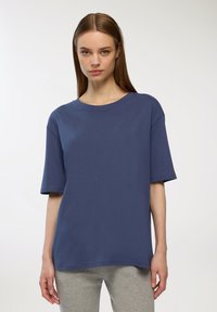 T-shirt blu navy a maniche corte in cotone morbido con scollatura rotonda e vestibilità rilassata, indossato con pantaloni felpa grigi.