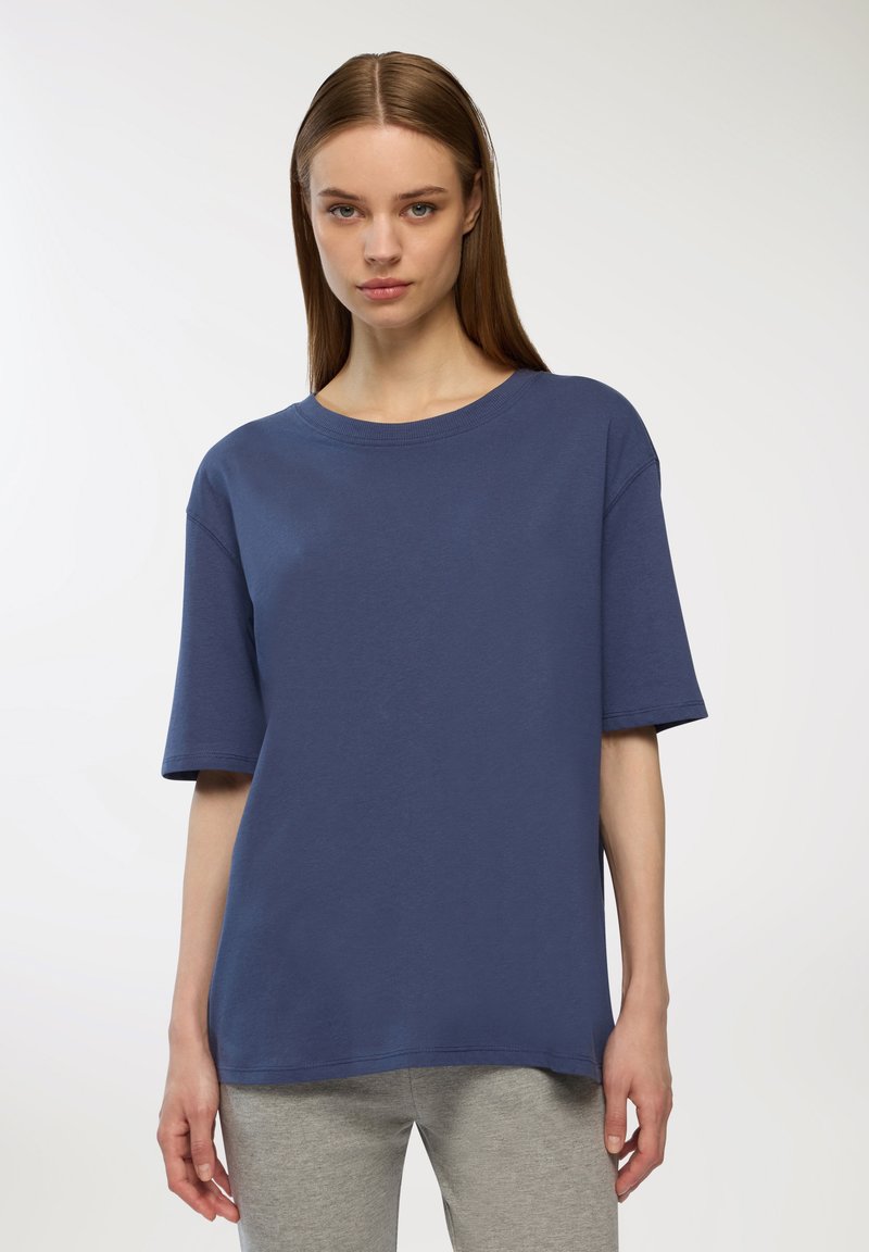 T-shirt blu navy a maniche corte in cotone morbido con scollatura rotonda e vestibilità rilassata, indossato con pantaloni felpa grigi.