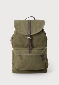 Zaino in tela verde oliva con patta pieghevole, cinturino in pelle marrone e tasca frontale. Presenta una superficie testurizzata e una forma arrotondata.