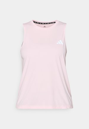 Bezrekawnik sportowy z jasnoróżowej tkaniny. Posiada okrągły dekolt, gładką fakturę oraz biały logo Adidas po lewej górnej stronie.