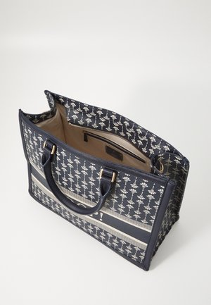 Sac fourre-tout bleu marine avec motif floral blanc, poignées noires, intérieur beige et poche intérieure zippée.