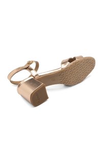 Sandalo con tacco a blocco in oro metallizzato, con cinturino regolabile e suola in gomma testurizzata con un motivo geometrico.