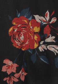 Blommönstrad tyg med stora röda och gula rosor med blå blad mot en svart bakgrund, kompletterad av ljusrosa blommor.