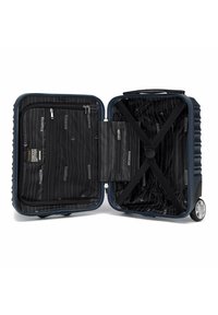 Valigia rigida di colore blu navy con una finitura texturizzata. L'interno presenta una fodera nera, tasche con cerniera e cinghie incrociate per fissare gli oggetti.