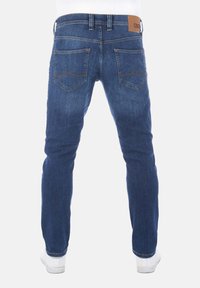 Jeans in denim con un lavaggio blu scuro, caratterizzati da una vestibilità slim, design a cinque tasche, cuciture a contrasto e una patch in pelle marrone sulla vita.