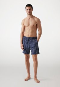 Costumi da bagno in tessuto blu navy con un motivo bianco ripetuto, vita elastica con cordino, tasche laterali e lunghezza a metà coscia.