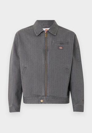 Szürke zipzáras munkakabát gallérral, mellkasi cipzáras zsebbel, oldalzsebekkel és egy kis logó folttal a mellkason és az ujján.