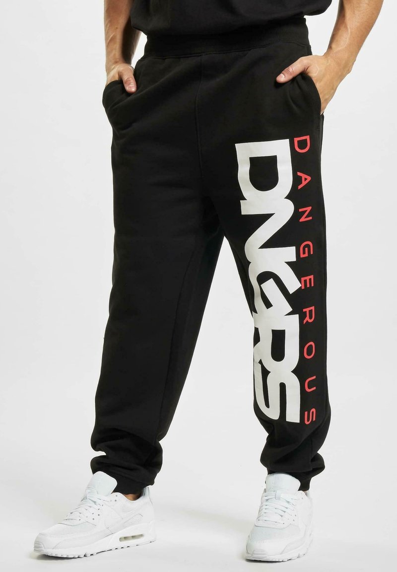 Pantaloni sportivi neri con design a gamba dritta. Presentano un grande testo "DANGEROUS" in bianco e rosso sul lato. Realizzati in tessuto morbido, con tasche.