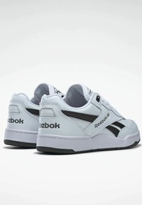 White Reebok sneakers with a smooth leather upper, black accents, and textured rubber sole; low-top design with padded collar and tongue.