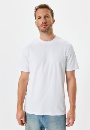 Witte katoenen t-shirt met een ronde halslijn, korte mouwen, een losse pasvorm en rechte zoom, gecombineerd met lichtblauwe spijkerbroek.