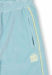 Helle blaue Jogginghose mit elastischem Bund, seitlichem Reißverschluss-Taschen, blassgelbem vertikalem Streifen und kleinem gesticktem Logo in der Nähe der Tasche.