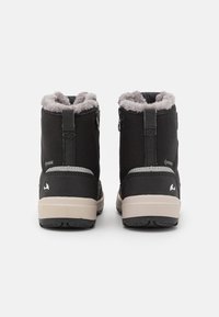 Botas impermeables negras con forro de pelo sintético gris, tejido de textura suave y suela beige en contraste. Presentan cremalleras laterales para un fácil uso.
