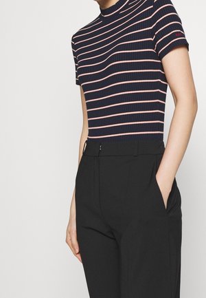 Camiseta de canalé con rayas azul marino y rosa, de cuello alto y mangas cortas, combinada con pantalones negros de corte recto con bolsillos laterales.