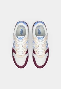 Αθλητικά παπούτσια με λευκή διχτυωτή επένδυση, μπεζ και ανοιχτό μπλε λεπτομέρειες, μπορντό σόλα και τρεις μπλε ρίγες. Διαθέτει σχέδιο με κορδόνια και λογότυπο στη γλώσσα.