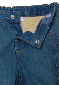 Pantaloni in denim blu con vita arricciata, chiusura a scatto e bottone, e cuciture a contrasto. Interno in tessuto beige.