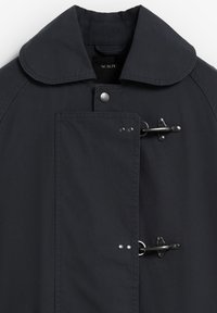 Cappotto blu scuro con colletto arrotondato, chiusure a toggles e tasca frontale con chiusure a scatto. Texture liscia e linee pulite.