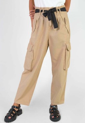 Beige cargobroek met een zwarte tailleband, voorzien van zijzakken en een losse pasvorm. Katoenen materiaal met een gladde textuur.