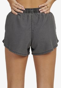 Hallid hallid sportlikud lühikesed püksid elastse vöökoha, kaarduva äärise ja siledaga. Koontrad kurvidel kontrastne õmblus.