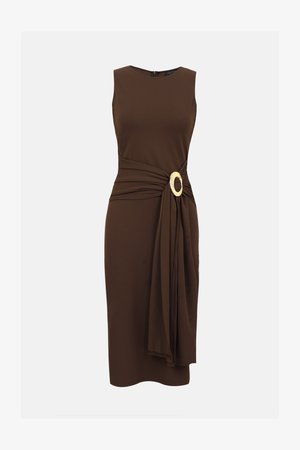 Ærmeløs mørkebrun midikjole med draperet stof samlet ved taljen, fastgjort med en stor oval guldspænde.