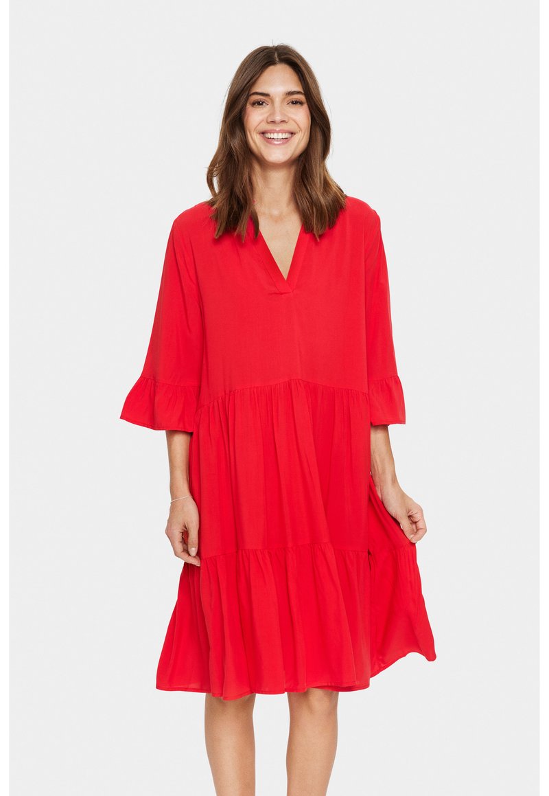 Robe rouge arrivant aux genoux en tissu léger, avec un décolleté en V, des manches trois-quarts et un design de jupe à volants avec des accents froncés.