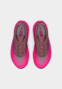 Ζευγάρι φωτεινά ροζ και καφέ αθλητικά παπούτσια για τρέξιμο με κορδόνια, ορατά από πάνω σε λευκό φόντο.