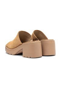 Mule in suede color cammello con tacco spesso beige. Il design presenta uno schienale aperto e punta rotonda, con una suola testurizzata.