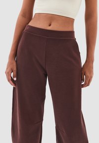 Bordeaux joggingbroek met een losse pasvorm, zachte textuur, elastische tailleband en zijzakken, voorzien van nette naden en minimale details.