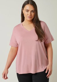 Rosa kortärmad t-shirt med v-ringning, av avslappnad passform och mjukt material, med en rundad nederkant och upprullade ärmslut.