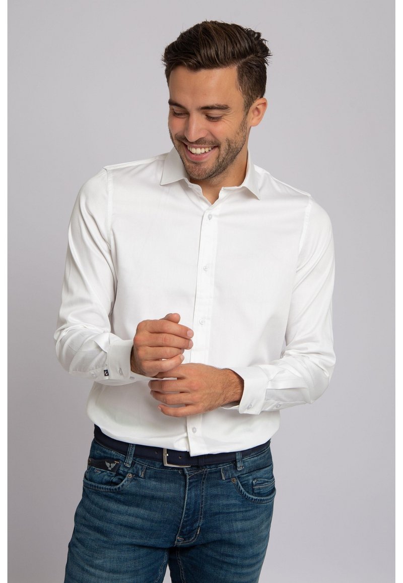 Wit overhemd met lange mouwen, een spreidkraag, knoopsluiting aan de voorkant en manchetten met één knoop, gecombineerd met een blauwe spijkerbroek en een donkere riem.