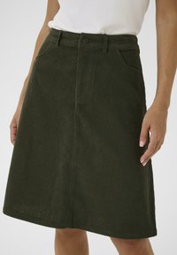 Groene corduroy rok met een rechte vorm, voorzien van een knoopsluiting, twee voorzakken en een gestructureerde stof. De zoom valt net boven de knie.