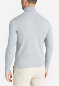 Maglione grigio chiaro a maniche lunghe a collo alto con una texture liscia e un design aderente, caratterizzato da un alto collo e una silhouette semplice e slanciata.