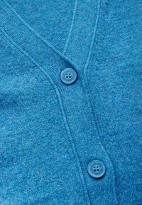 Blå stickad cardigan med V-ringning, med två runda, ljusblå knappar. Tyget har en mjuk textur och en melerad finish.