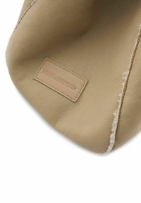 Borsa in pelle beige con una finitura testurizzata, caratterizzata da una cucitura e un'etichetta rettangolare impressa con la scritta "FREDsBRUDER."