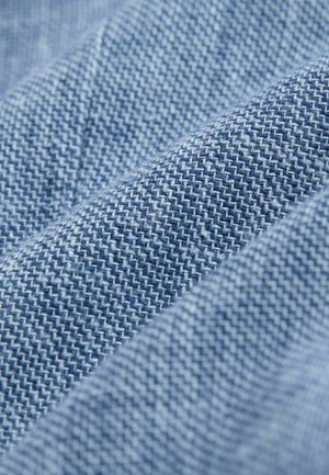 Kék halszálka mintás farmeranyag, texturált felülettel és különböző kék árnyalatokkal, összegyűrve és rétegezve.