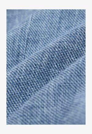 Kék halszálka mintás farmeranyag, texturált felülettel és különböző kék árnyalatokkal, összegyűrve és rétegezve.