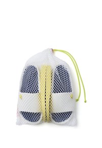 Bolsa de malla con cordón que contiene chanclas azul y amarillas, con una suela blanca y correas texturizadas. La bolsa presenta un cordón de color verde brillante.